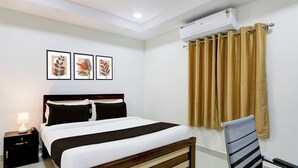 Una habitación de hotel con una cama, una silla, una mesita de noche y un aire acondicionado.