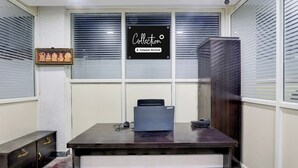 Una habitación con un escritorio, una computadora, un cuadro enmarcado y un cartel en la ventana.