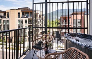 Ein Balkon mit Korbstühlen, einem Whirlpool und einer Weinflasche.