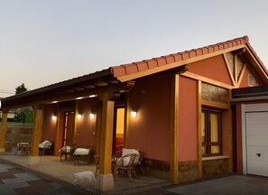 A building with a covered patio area, a garage, and outdoor seating. - Apartment with Terrace, Pool, and Mountain Views (Miengo)