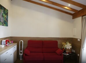 A room with a red sofa, a small table with a vase of flowers, and a painting on the wall. - Apartment with Terrace, Pool, and Mountain Views (Miengo)