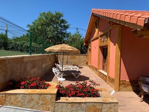 A sunlit outdoor area with a pool, lounge chairs, a thatched umbrella, and red flowers. - Studio with Terrace and Pool (Miengo)