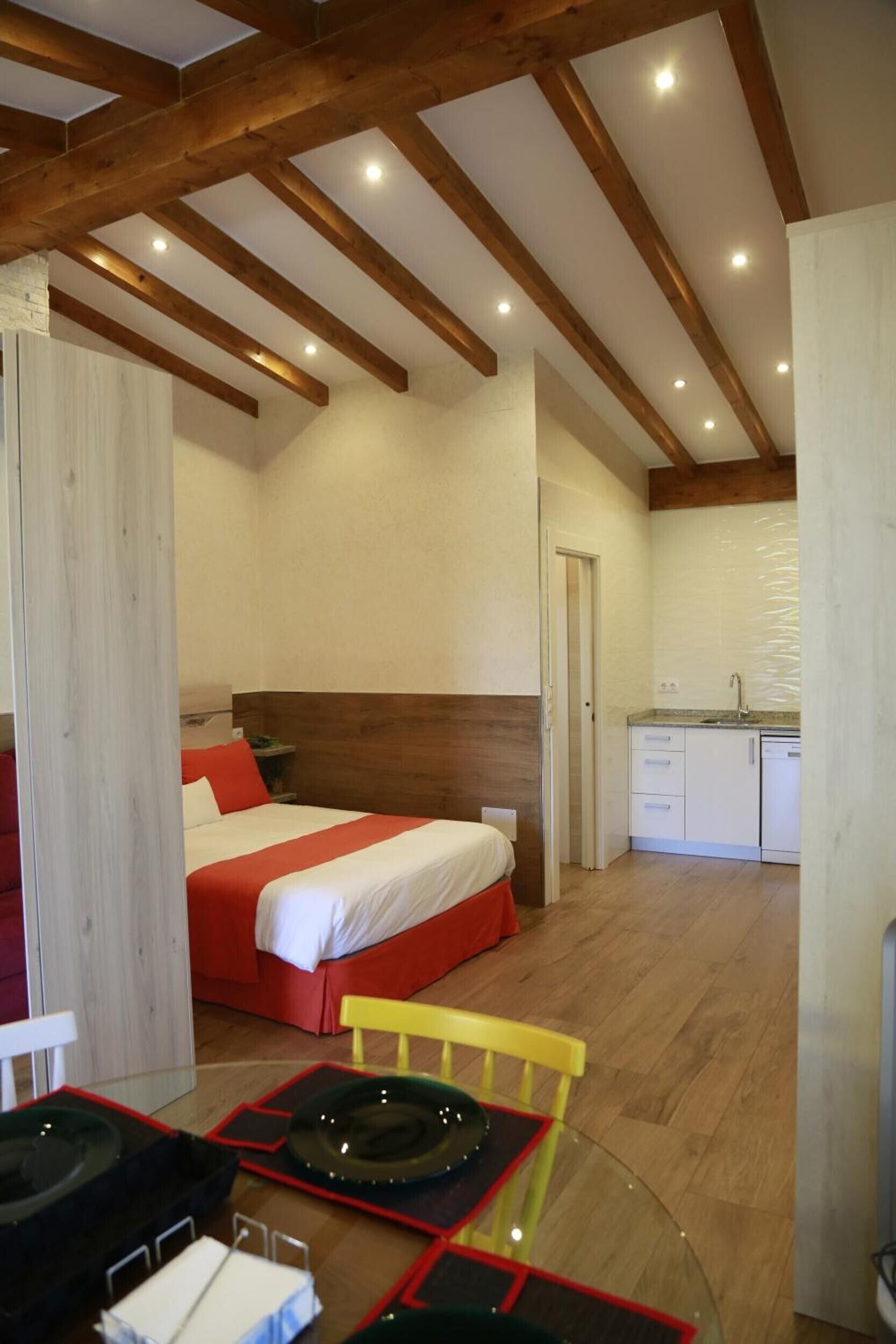 A hotel room with a bed, a kitchenette, and a dining area with a table and chairs.