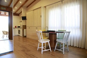 A dining area with a table and chairs, a kitchen in the background, and a window with curtains. - Studio with Terrace and Pool (Miengo)