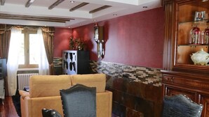 A living room with a sofa, a dining table with chairs, a fireplace, and a wooden cabinet with decorative items. - Casa La Arena with Pool (Miengo)