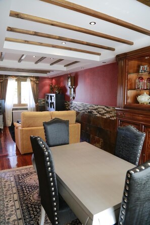 Ein Wohnzimmer mit einer Couch, einem Esstisch mit Stühlen, einem Kamin und einer Holzkabine mit Dekoration.