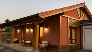 A building with a covered patio area, multiple chairs, and a white garage door. - Casa La Arena with Pool (Miengo)
