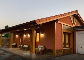 Ein Gebäude mit überdachter Terrasse, mehreren Sitzgelegenheiten und einer weißen Garagentür.