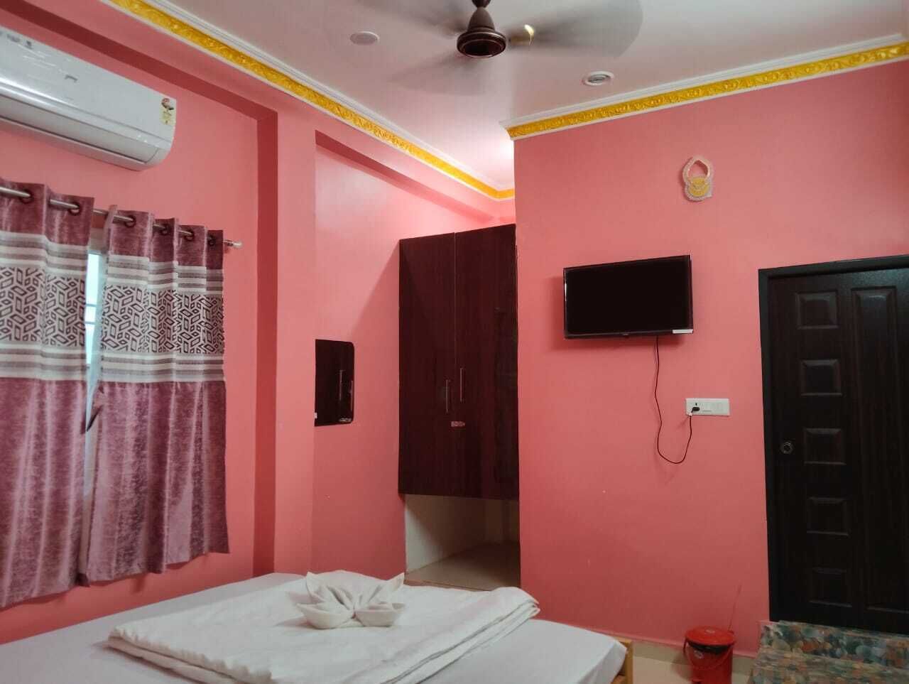Una habitación con cama, televisor, aire acondicionado, armario y puerta.
