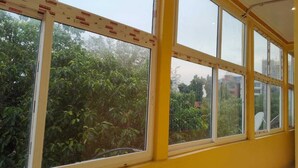 A room with large windows, a yellow wall, and visible construction materials. - Hotel Ashirwad And Marriage Hall (Deoghar)