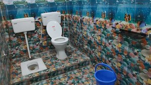 A bathroom with a toilet, bidet, and shower area, decorated with a fish-themed mural. - Hotel Ashirwad And Marriage Hall (Deoghar)