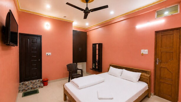 A bedroom with a bed, a ceiling fan, a television, a wardrobe, and a door. - Hotel Ashirwad And Marriage Hall (Deoghar)