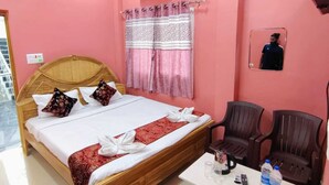 A hotel room with a bed, a bedside table with a remote control, a water bottle, and a mirror on the wall. - Hotel Ashirwad And Marriage Hall (Deoghar)