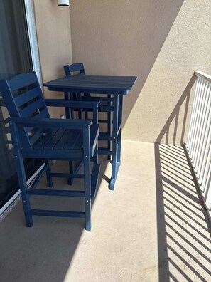 Ein Balkon mit Tisch und Stühlen, einem Geländer und Blick auf das äußere Erscheinungsbild des Gebäudes.