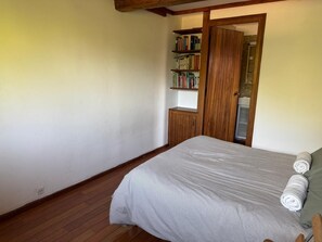 A bedroom with a bed, a wooden wardrobe, and a bookshelf. - La Grange du Vaudoué (Le Vaudoué)