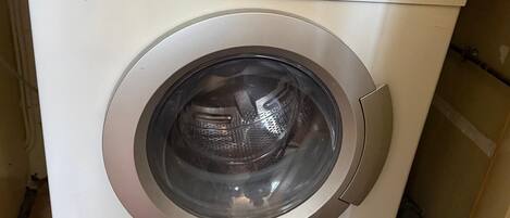 A white Siemens washing machine with a control panel, located in a room with wooden flooring.