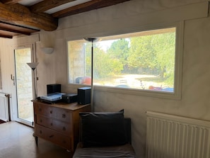 Ein Zimmer mit einem Bett, einem Schminktisch, einem Fenster mit Blick auf Bäume und einer Heizung.
