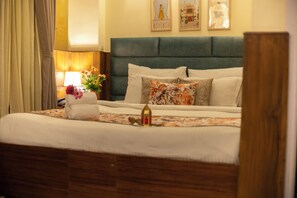 Una habitación de hotel con cama, mesita de noche, lámpara y un florero con flores.