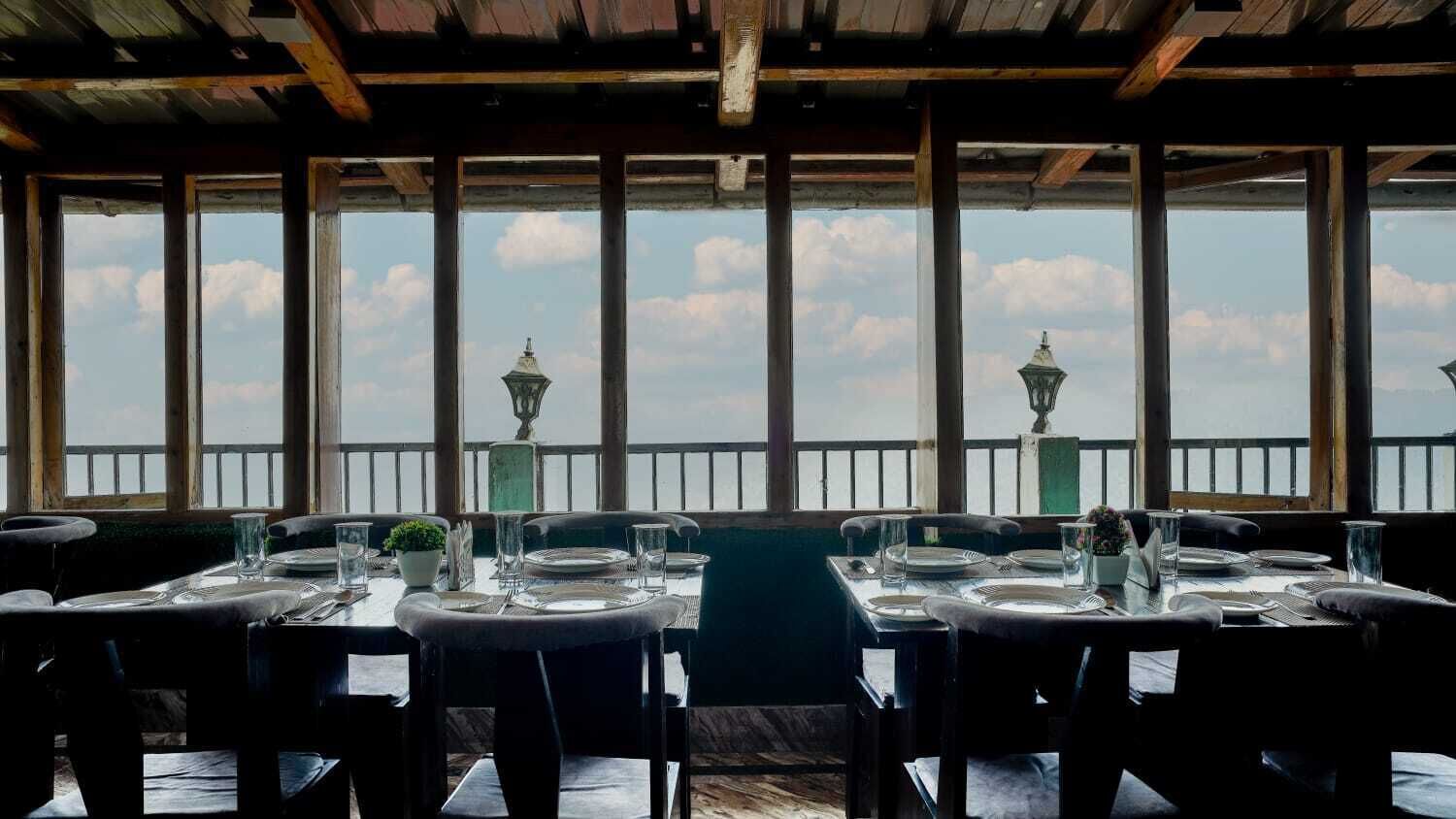 Un restaurant offrant une vue sur les toits d’une ville, avec une longue table dressée pour le dîner.
