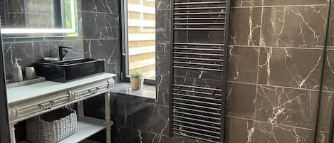 Une salle de bain équipée d’un meuble-lavabo, d’un miroir, d’un porte-serviettes et d’une fenêtre donnant sur une clôture en bois.