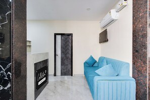 Una habitación con un sofá azul, una chimenea y una puerta.