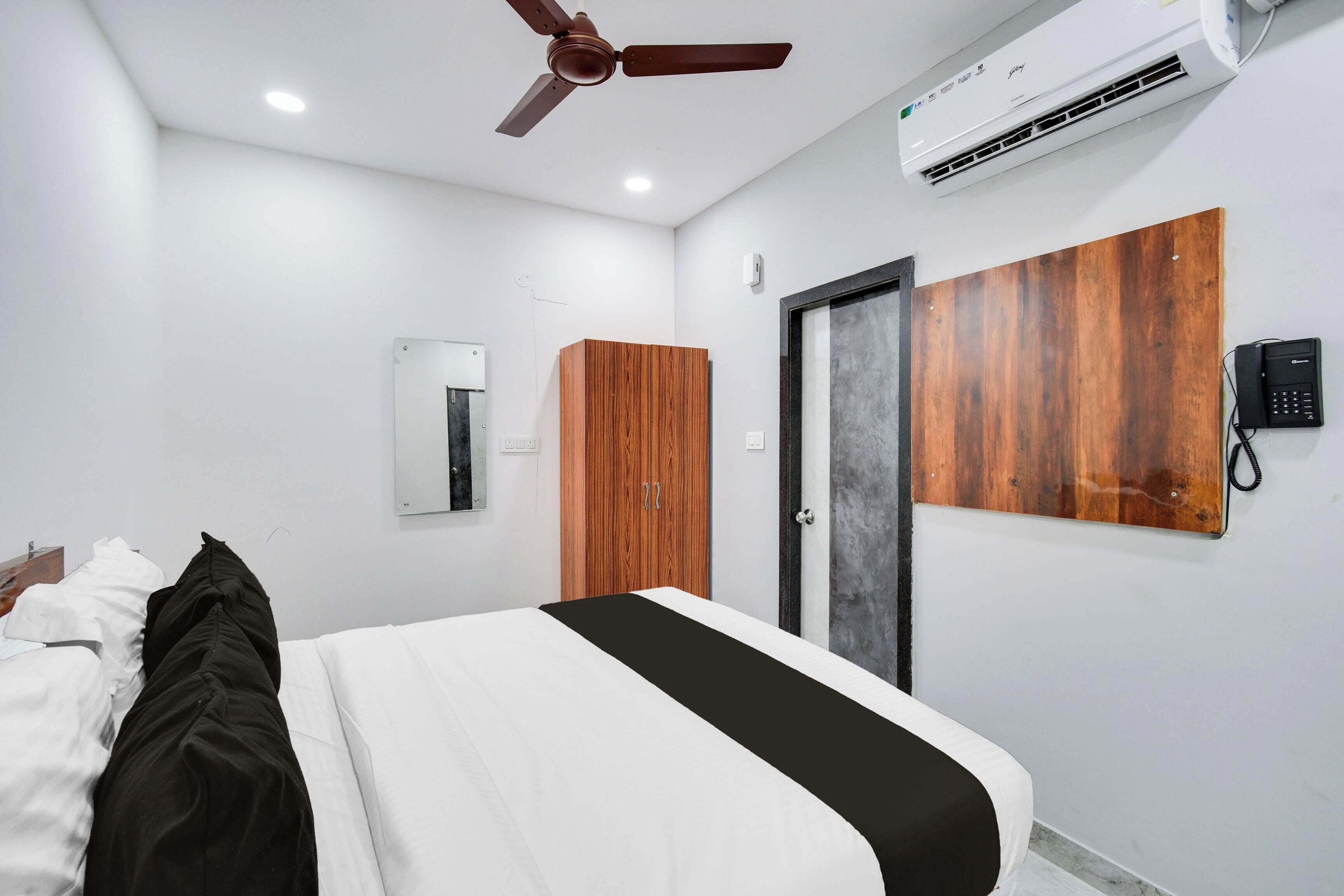 Een hotelkamer met een bed, een kledingkast, een spiegel, een airconditioning en een telefoon.