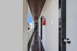 Ein Korridor mit an der Wand montiertem Feuerlöscher, einer Tür mit Metallbeschlägen und einer Decke mit Holzpaneelen.