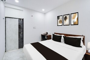 Una habitación de hotel con una cama, una mesita de noche, una lámpara de pared y una puerta.