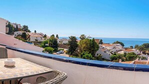 A balcony with a table and chairs, overlooking a coastal town. - Capuchinos, San Juan de Capistrano (Nerja)
