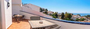 Ein Balkon mit Tisch und Stühlen mit Blick auf eine Küstenstadt.