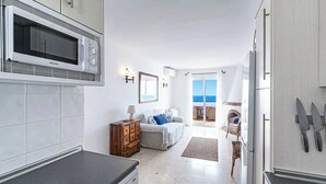 A modern kitchen with a microwave, cabinets, and a dining area with a view of the sea. - Capuchinos, San Juan de Capistrano (Nerja)