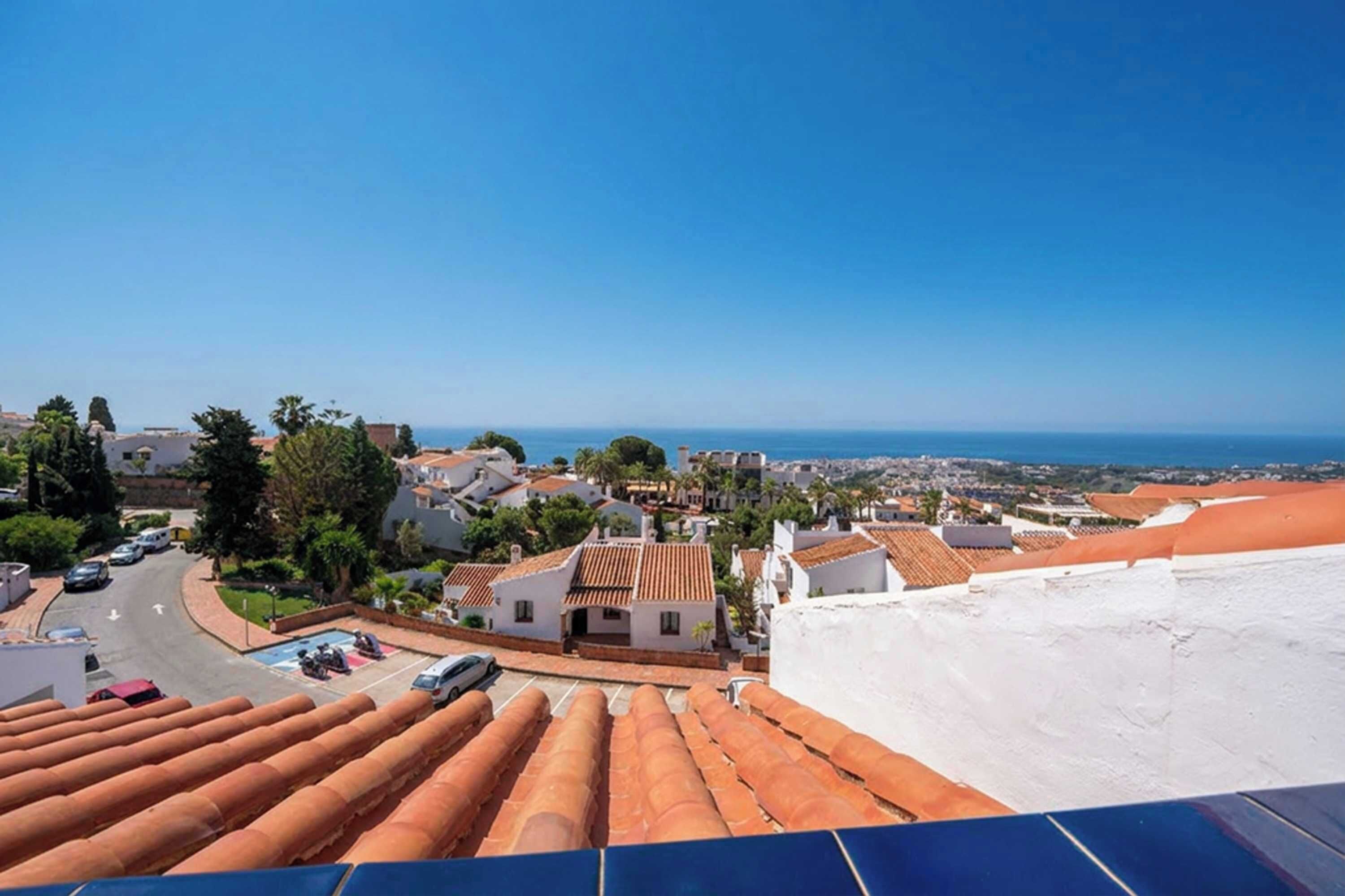Eine Küstenstadt mit Häusern mit Terrakotta-Dächern, blauem Himmel und Blick auf das Meer.