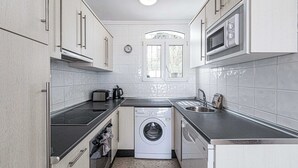 A compact kitchen with a washing machine, a microwave, and a toaster. - Capuchinos, San Juan de Capistrano (Nerja)