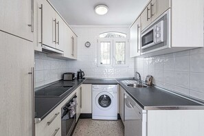 Eine kleine Küche mit Waschmaschine, Mikrowelle und Toaster.