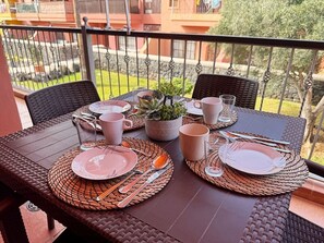 A dining table set outdoors with plates, cutlery, and a potted plant. - Atlantico Apartment: Air Conditioning, Swimming Pool (Santa Cruz de Tenerife)