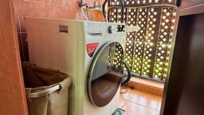 A laundry area with a washing machine, a drying rack, and a tiled floor. - Atlantico Apartment: Air Conditioning, Swimming Pool (Santa Cruz de Tenerife)