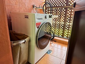 Ein Waschbereich mit Waschmaschine, Wäscheständer und Fliesenboden.