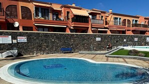 A swimming pool with a stone wall and a building in the background. - Atlantico Apartment: Air Conditioning, Swimming Pool (Santa Cruz de Tenerife)