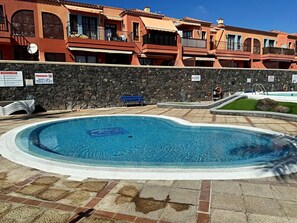 Ein Schwimmbecken mit einer Steinmauer und einem Gebäude im Hintergrund.