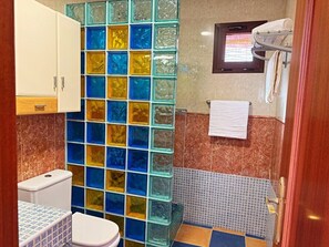 A bathroom with a toilet, a sink, a glass block partition, a towel rack, and a window. - Atlantico Apartment: Air Conditioning, Swimming Pool (Santa Cruz de Tenerife)