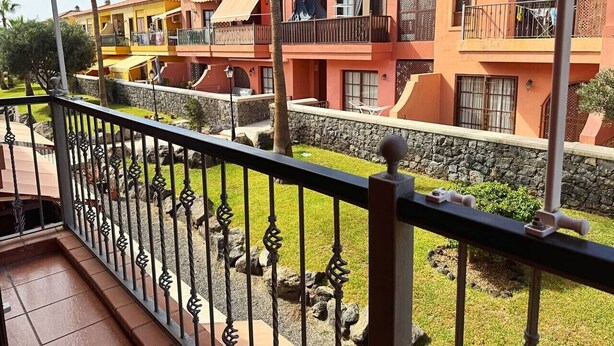 A balcony with a stone wall and a grassy area in the background. - Atlantico Apartment: Air Conditioning, Swimming Pool (Santa Cruz de Tenerife)