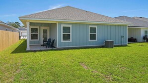 A single-story house with a covered porch, a small lawn, and a clear sky. - Home with Pickleball Courts, Wifi & Beach Essentials (Navarre)
