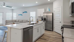 A modern kitchen with white cabinetry, a stainless steel refrigerator, and a built-in dishwasher. - Home with Pickleball Courts, Wifi & Beach Essentials (Navarre)