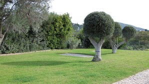 A landscaped garden with manicured grass, a paved walkway, and neatly trimmed trees. - Charming Villa With 3 Bedrooms and sea View (Faro)