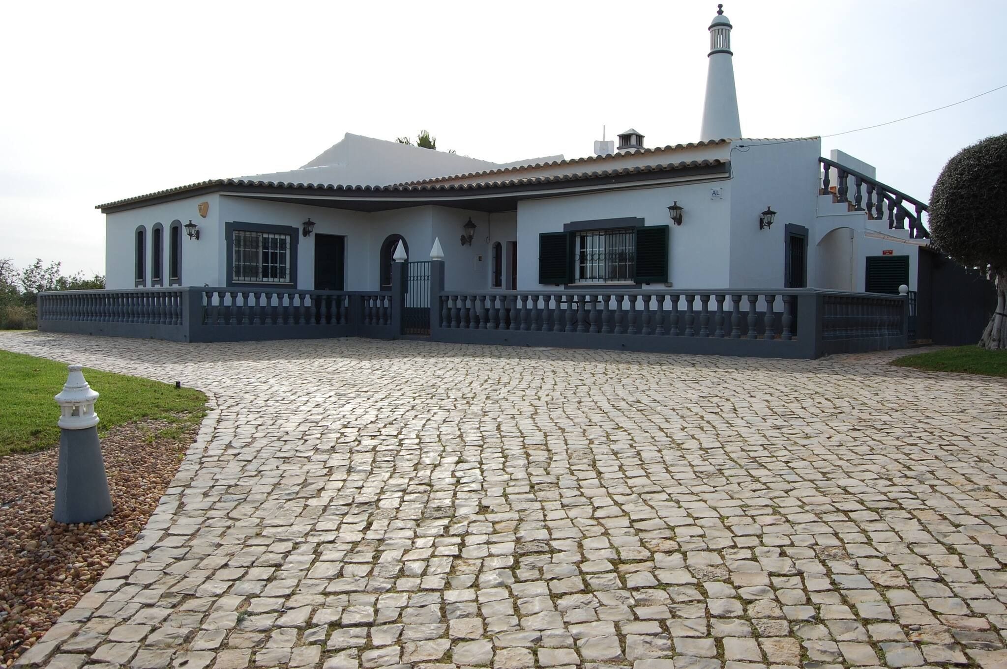 A building with a tiled roof, a white facade, and a stone-paved entrance.