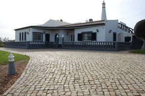 A building with a tiled roof, a white facade, and a stone-paved entrance. - Charming Villa With 3 Bedrooms and sea View (Faro)