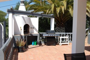 An outdoor patio with a brick floor, a barbecue grill, a pizza oven, and a white pergola structure. - Charming Villa With 3 Bedrooms and sea View (Faro)