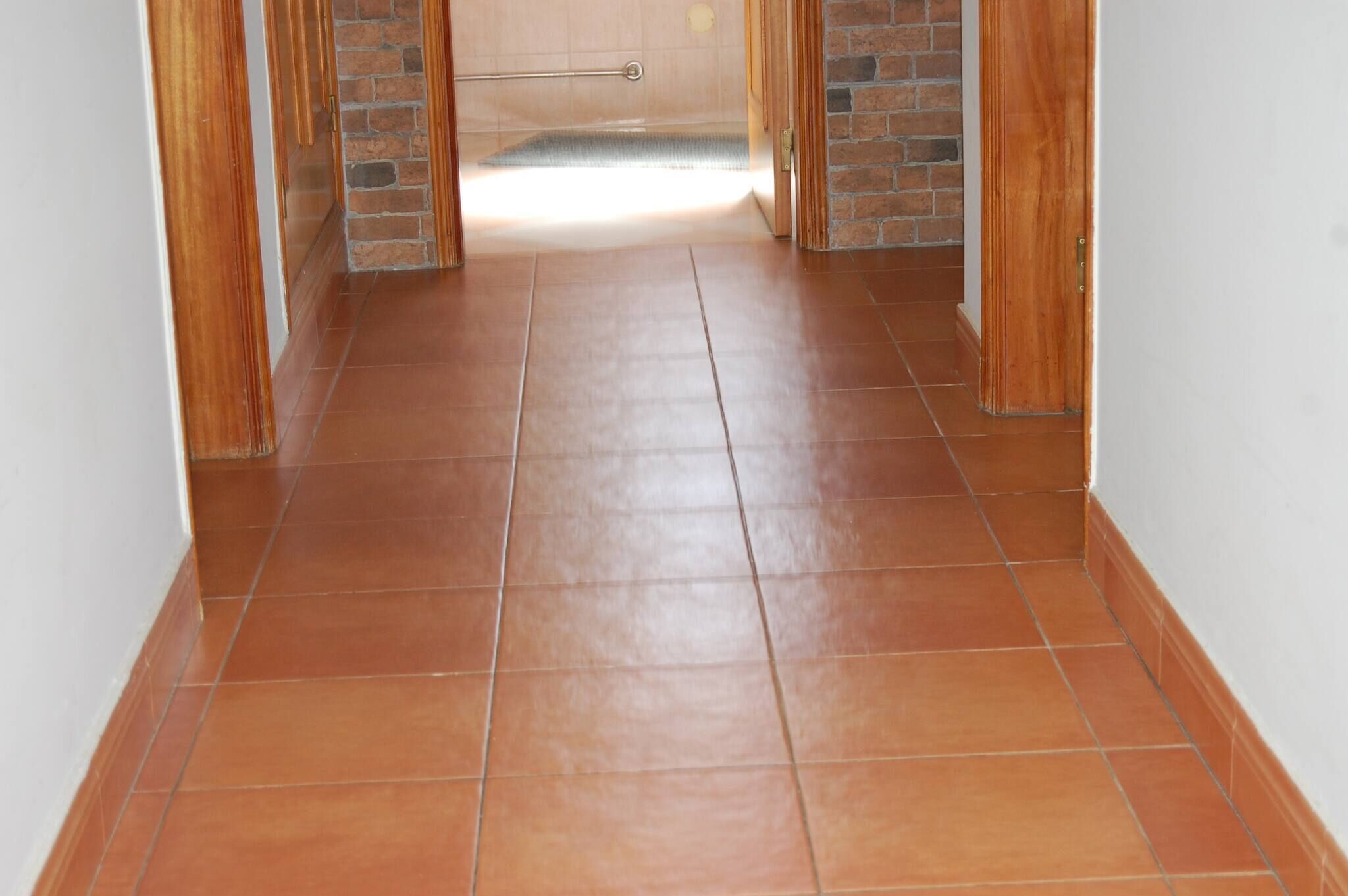 A hallway with tiled flooring and wooden walls.