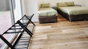 Una camera da letto con due letti, una finestra e pavimento in legno.