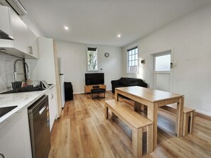 Una cocina moderna con lavavajillas, un lavamanos y una mesa de comedor de madera con bancos.